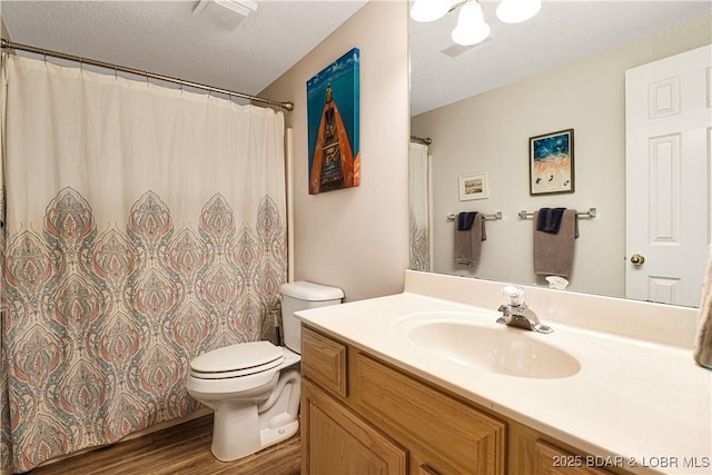 bathroom featuring toilet, a textured ceiling, wood finished floors, and vanity