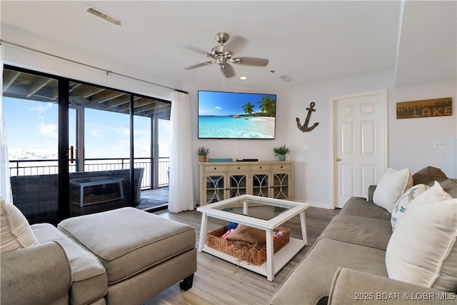 living room with ceiling fan, visible vents, a wealth of natural light, and wood finished floors