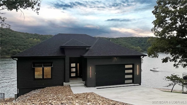 view of front facade with a garage, driveway, and a shingled roof