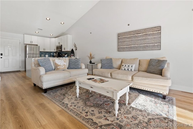 living room with baseboards, high vaulted ceiling, light wood-type flooring, and recessed lighting