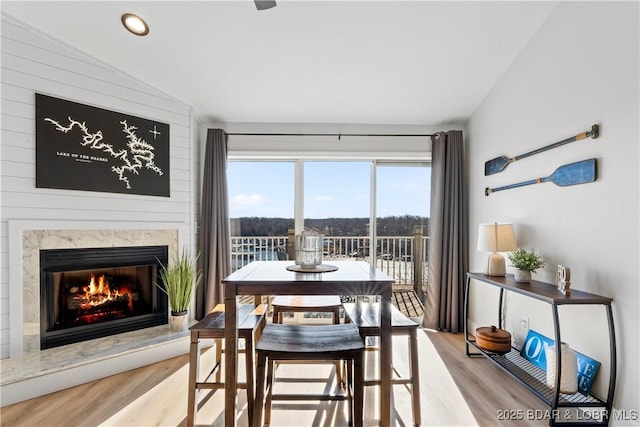 dining area featuring a high end fireplace, lofted ceiling, recessed lighting, and wood finished floors