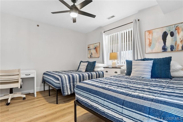 bedroom with ceiling fan, wood finished floors, visible vents, and baseboards