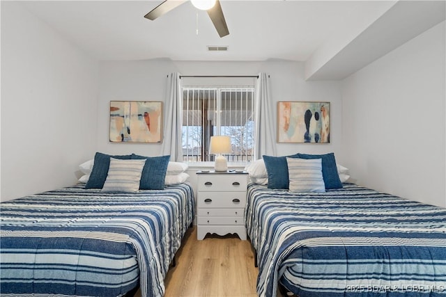 bedroom with a ceiling fan, visible vents, and wood finished floors