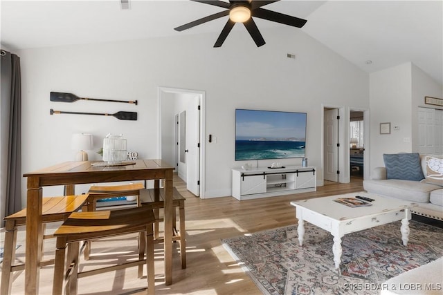 living area with high vaulted ceiling, light wood-type flooring, and ceiling fan