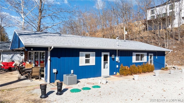 ranch-style house with central AC, a shingled roof, and a patio area