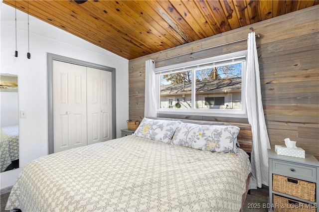 bedroom with a closet, lofted ceiling, wooden ceiling, and wood walls