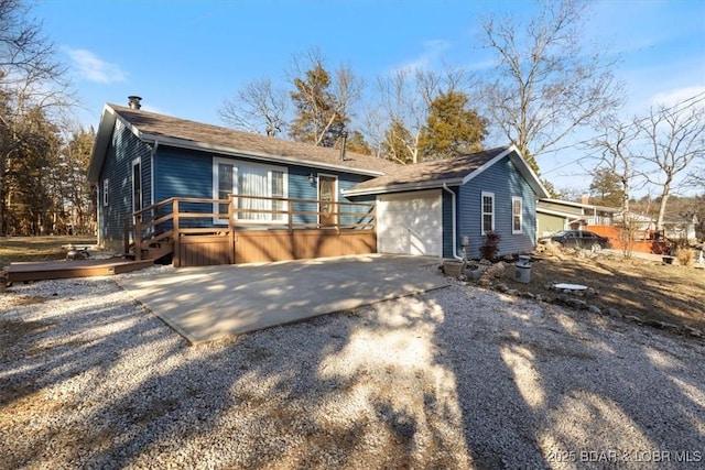 view of front facade with a garage, an outbuilding, concrete driveway, and a deck