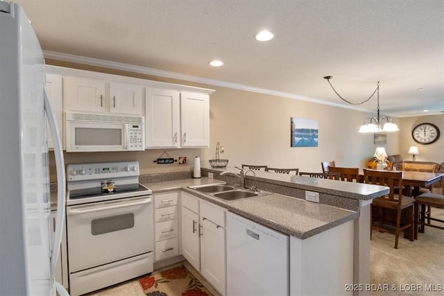 kitchen with crown molding, white cabinets, a sink, white appliances, and a peninsula