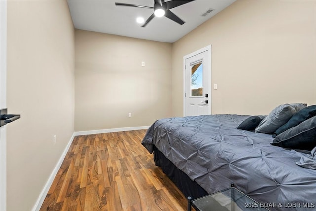 bedroom featuring a ceiling fan, wood finished floors, visible vents, and baseboards