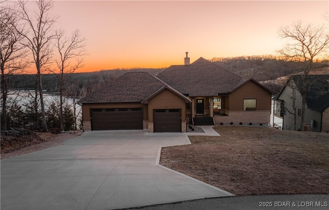 view of front of home featuring roof with shingles, driveway, and an attached garage