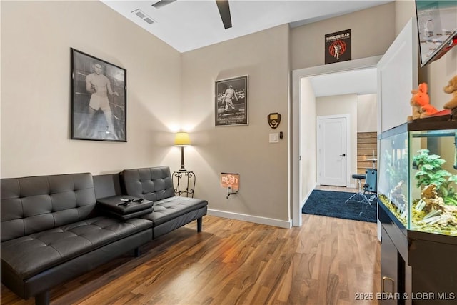 living room with ceiling fan, visible vents, baseboards, and wood finished floors