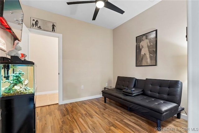 sitting room with a ceiling fan, baseboards, and wood finished floors