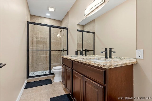 bathroom featuring double vanity, a stall shower, toilet, tile patterned flooring, and a sink