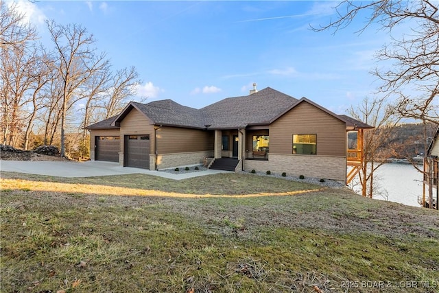 view of front of house with a front yard, roof with shingles, driveway, and an attached garage