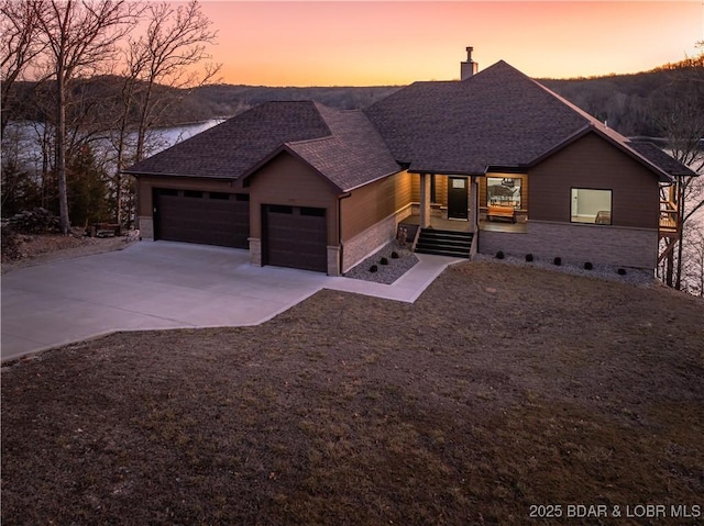 view of front of home featuring an attached garage, driveway, a chimney, and roof with shingles