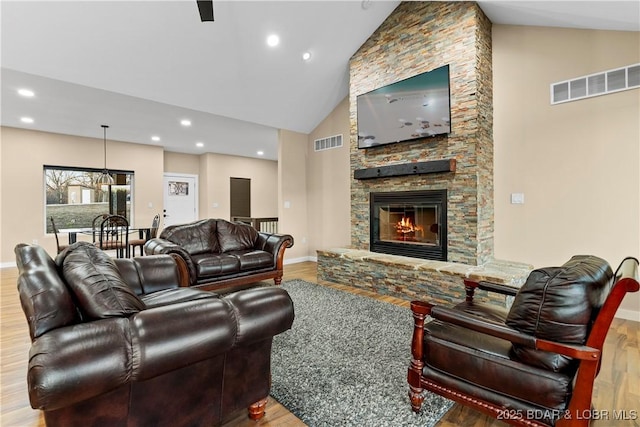 living area featuring a fireplace, visible vents, and wood finished floors