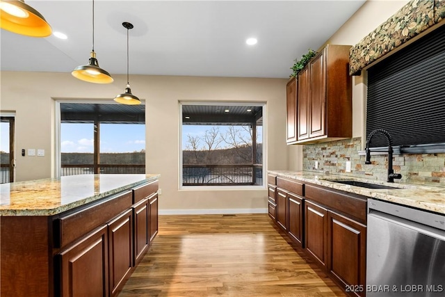 kitchen featuring a sink, decorative backsplash, dishwasher, light wood finished floors, and pendant lighting