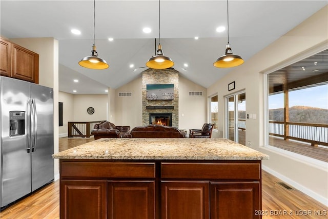 kitchen with visible vents, stainless steel fridge with ice dispenser, and light stone countertops