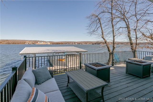 wooden deck with an outdoor living space with a fire pit and a water view