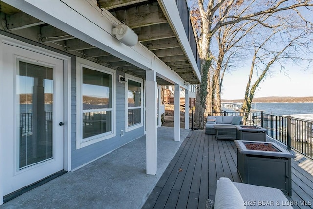 wooden deck with a water view and an outdoor living space with a fire pit