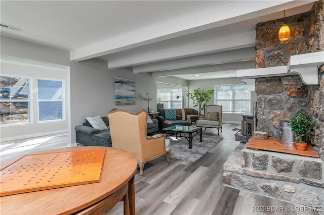 living area with baseboards, visible vents, wood finished floors, and beamed ceiling