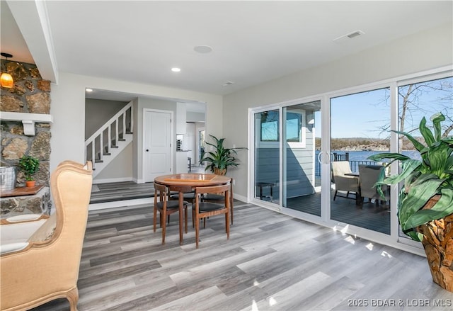 dining space with baseboards, visible vents, stairway, and wood finished floors