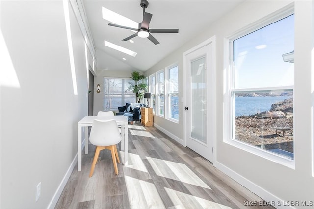 sunroom with lofted ceiling with skylight, a water view, and a ceiling fan