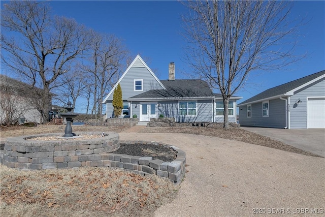 view of front facade featuring concrete driveway, french doors, and a chimney