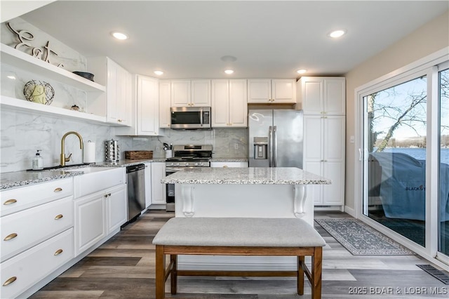 kitchen featuring light stone countertops, a sink, white cabinets, appliances with stainless steel finishes, and decorative backsplash