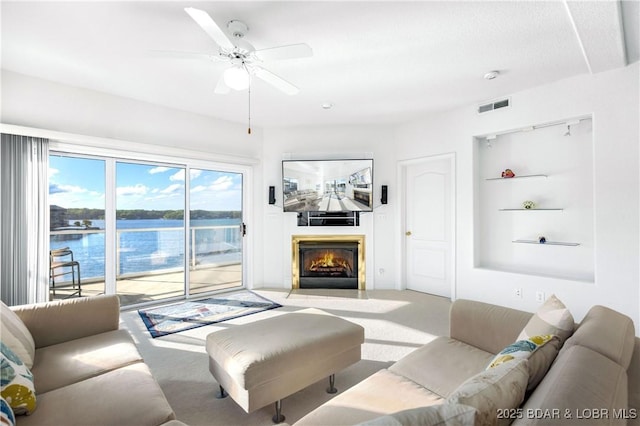 carpeted living room featuring a fireplace with flush hearth, visible vents, and a ceiling fan