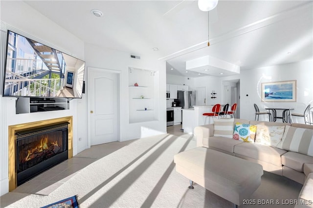 living room featuring a glass covered fireplace and visible vents