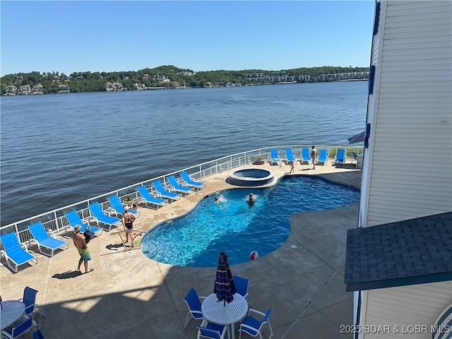 view of swimming pool with a pool with connected hot tub, a patio area, and a water view