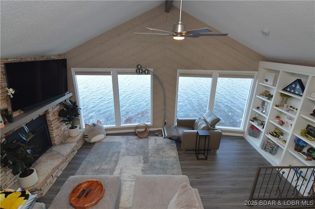 living area featuring a fireplace, lofted ceiling with beams, wooden walls, a textured ceiling, and wood finished floors