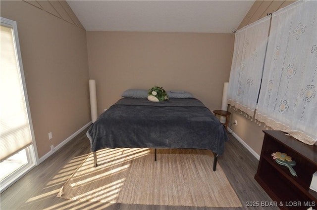 bedroom with lofted ceiling, baseboards, and wood finished floors