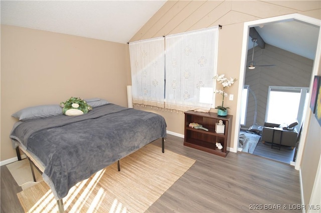 bedroom featuring lofted ceiling, baseboards, and wood finished floors