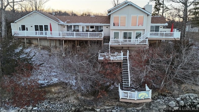 back of house with stairs, a chimney, and a wooden deck