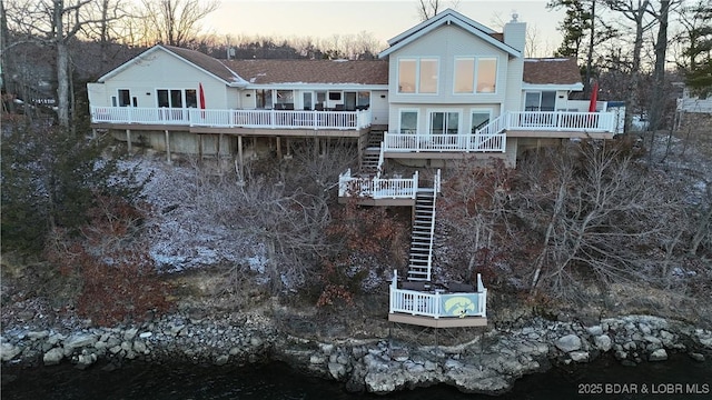 back of property at dusk featuring a chimney, stairway, and a wooden deck