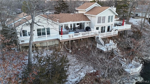 rear view of property featuring a deck, a chimney, a shingled roof, and stairway