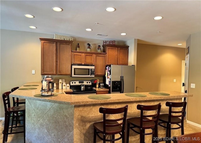 kitchen with appliances with stainless steel finishes, a breakfast bar, visible vents, and recessed lighting