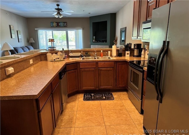 kitchen featuring light tile patterned floors, stainless steel appliances, open floor plan, a sink, and a peninsula