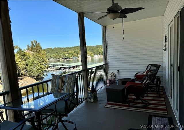 balcony with a water view and a ceiling fan