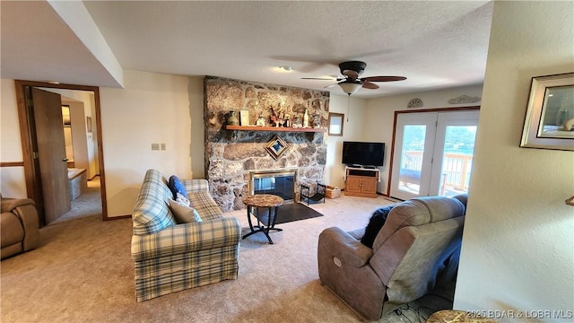 living room featuring light carpet, ceiling fan, a stone fireplace, and a textured ceiling