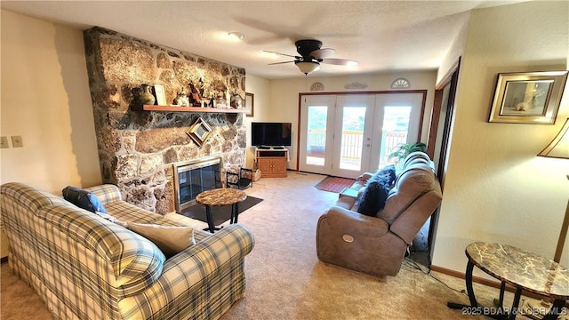 living room featuring light carpet, a fireplace, a ceiling fan, baseboards, and french doors