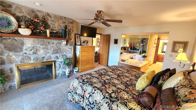 bedroom featuring tile patterned floors, a ceiling fan, and a stone fireplace