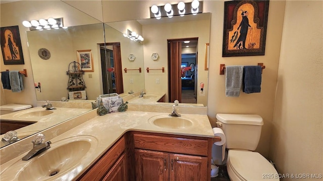 bathroom featuring toilet, double vanity, and a sink