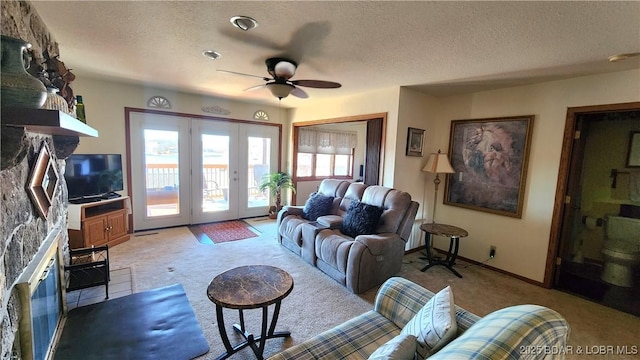 living area with light carpet, baseboards, a ceiling fan, and a textured ceiling