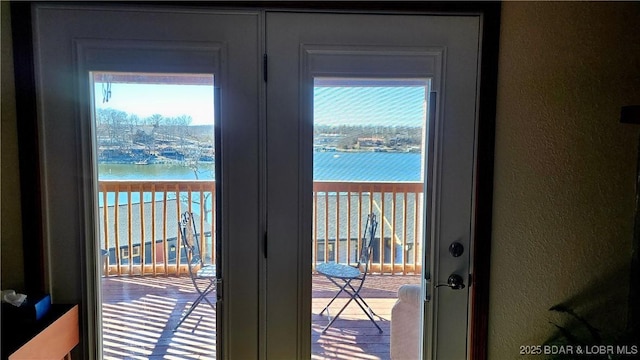 doorway featuring a textured wall, french doors, a water view, and a healthy amount of sunlight