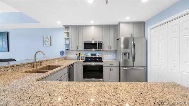 kitchen with stainless steel appliances, open shelves, gray cabinets, and a sink