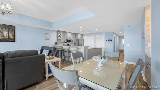 dining area with recessed lighting, a notable chandelier, light wood-style flooring, and baseboards