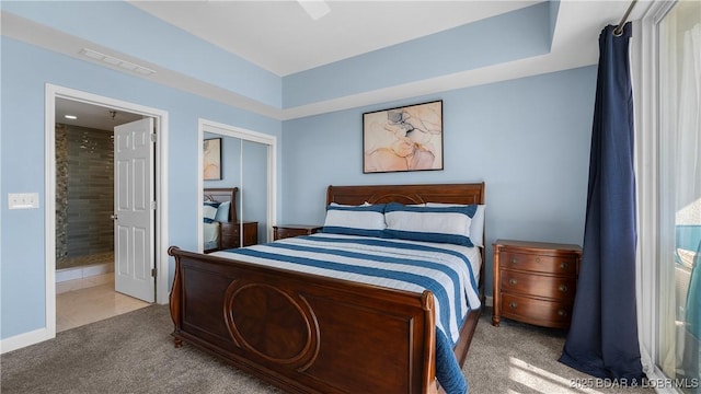 carpeted bedroom featuring visible vents, baseboards, a ceiling fan, a closet, and ensuite bath